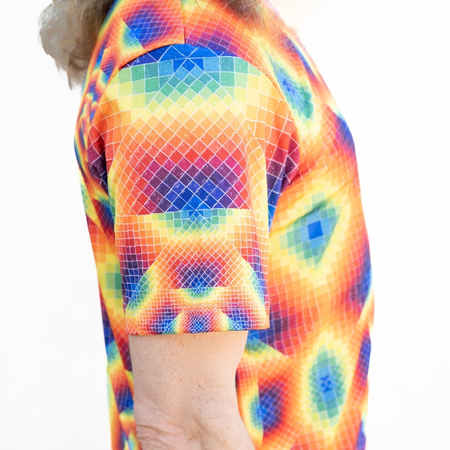 CoSM Shop men's short-sleeve performance polyester t-shirt with a vibrant rainbow geometric all-over print.