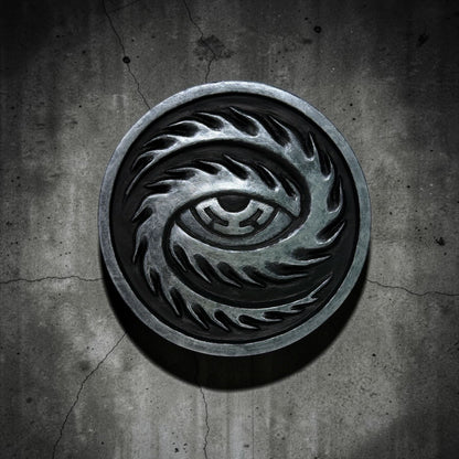 CoSM Shop Cosmic Eye wall emblem, a circular resin cast hand-painted with a stylized eye design in metallic silver and black.