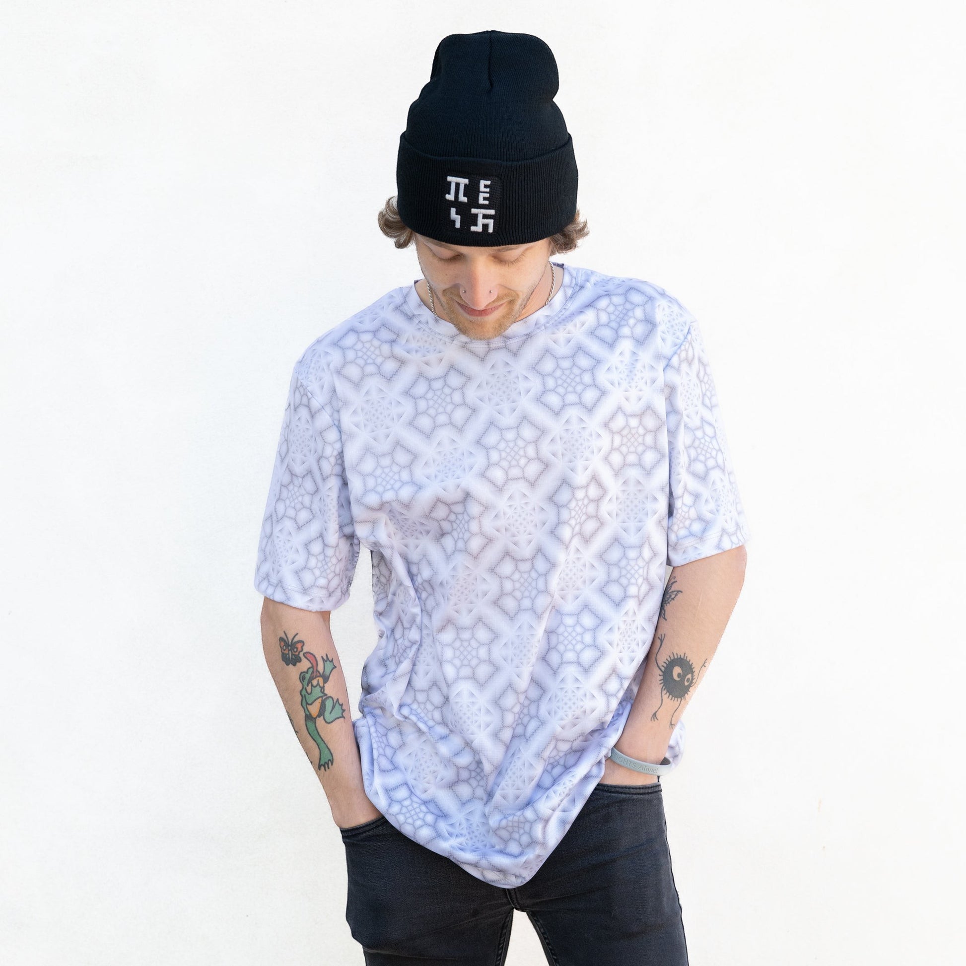 CoSM Shop men's short-sleeve dye-sublimation t-shirt in white with a grey geometric pattern. Model wears a black beanie.