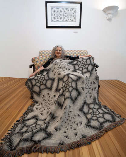 CoSM Shop Inkwash art blanket with a geometric grey scale pattern, made of recycled cotton.