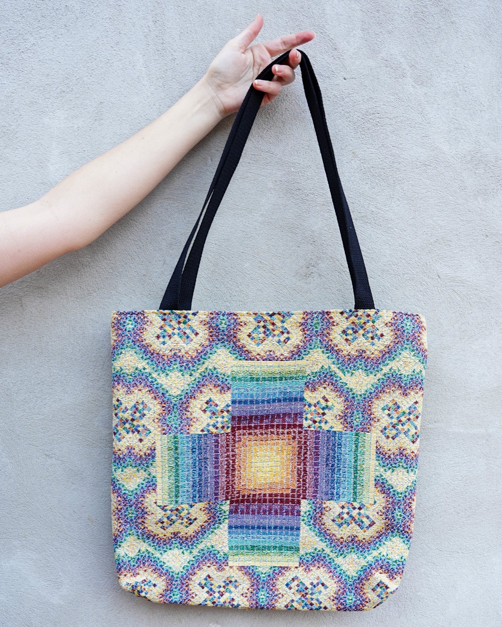 CoSM Shop Rainbow Cross woven tote bag with colorful geometric pattern and black straps, made of 100% cotton.