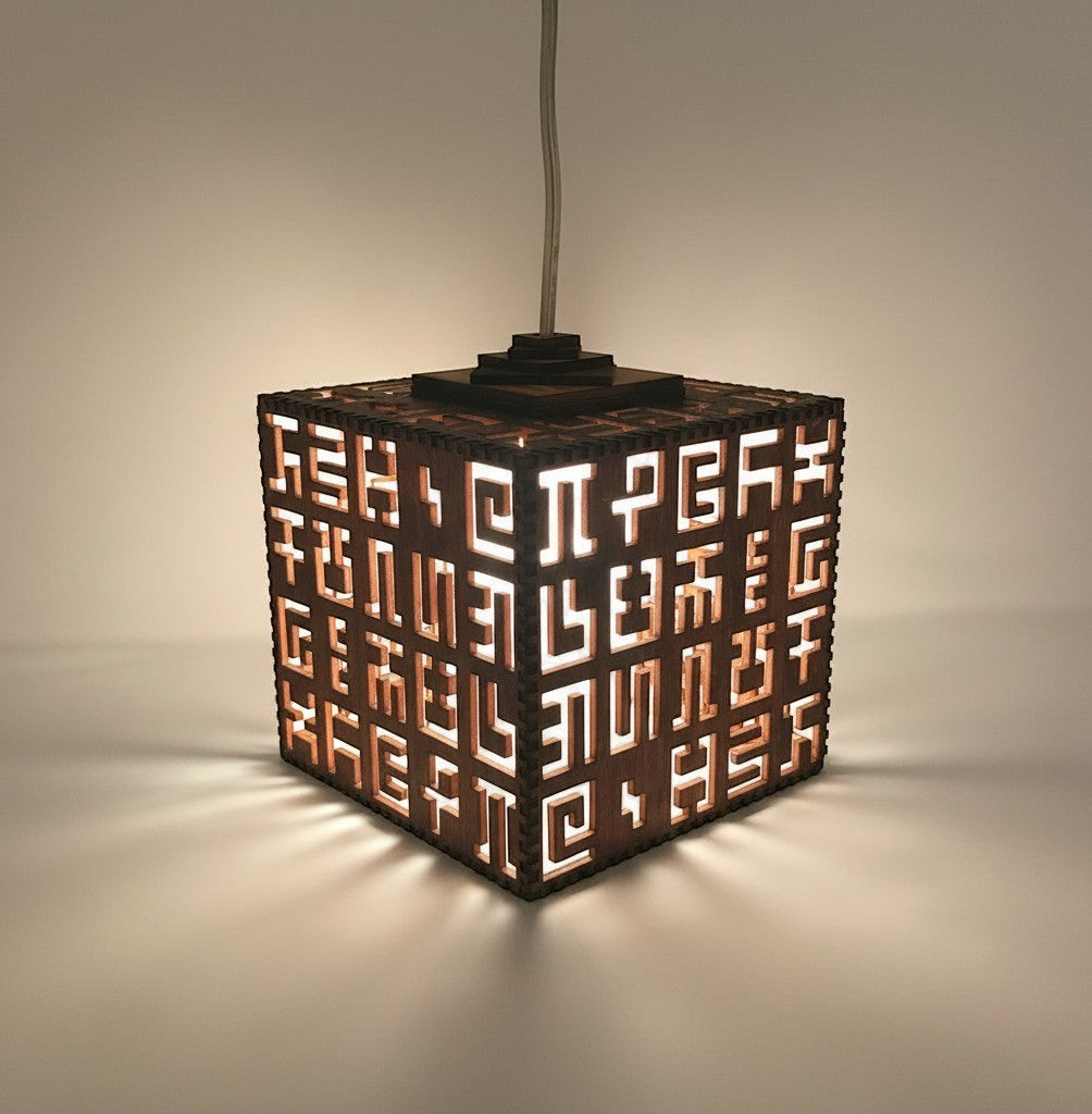 CoSM Shop Secret Writing hanging lamp made of laser cut birch wood with intricate geometric patterns and text.