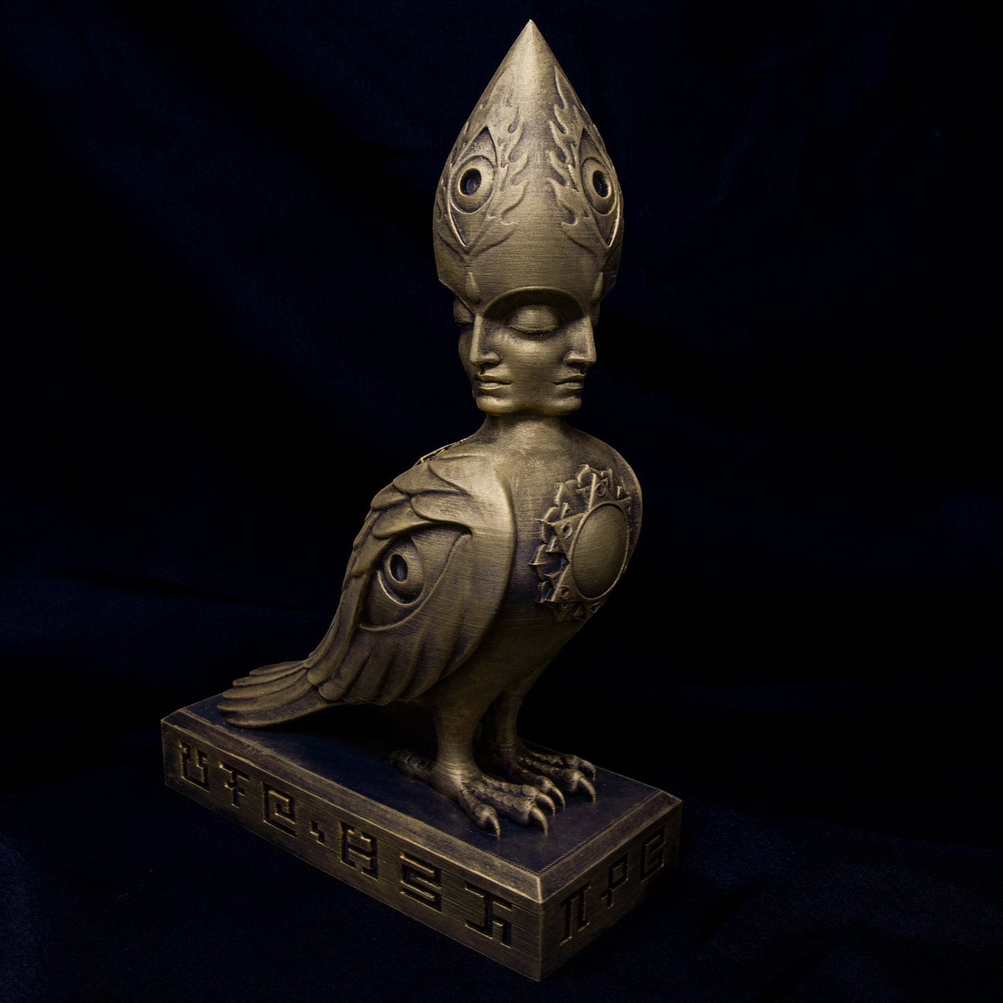 CoSM Shop Soulbird sculpture: a golden, hand-painted bird with a four-faced head, wings with eyes, and a sun symbol on its chest.
