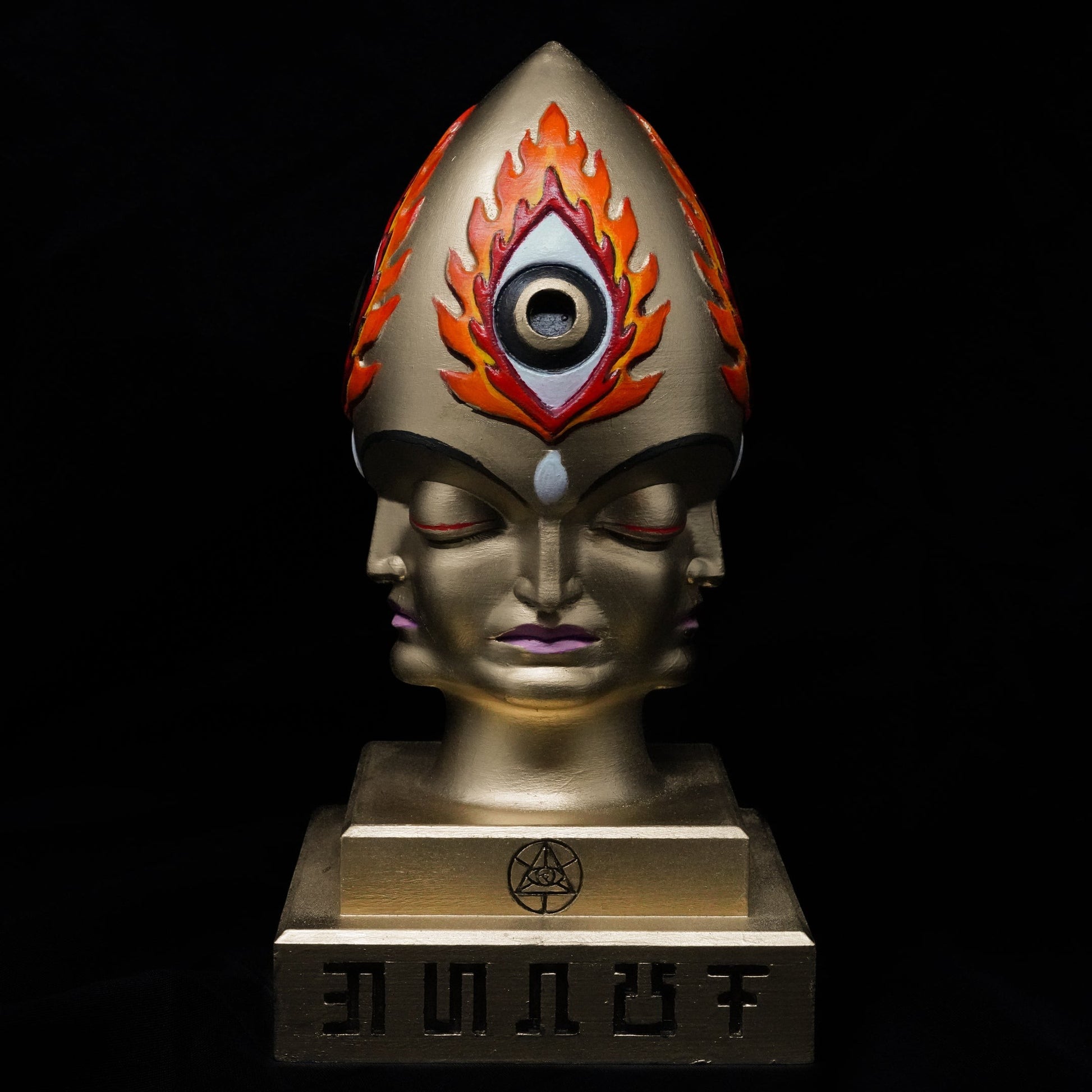 CoSM Shop Steeplehead sculpture by Alex Grey, hand-painted gold with a third eye and flames, featuring multiple faces.