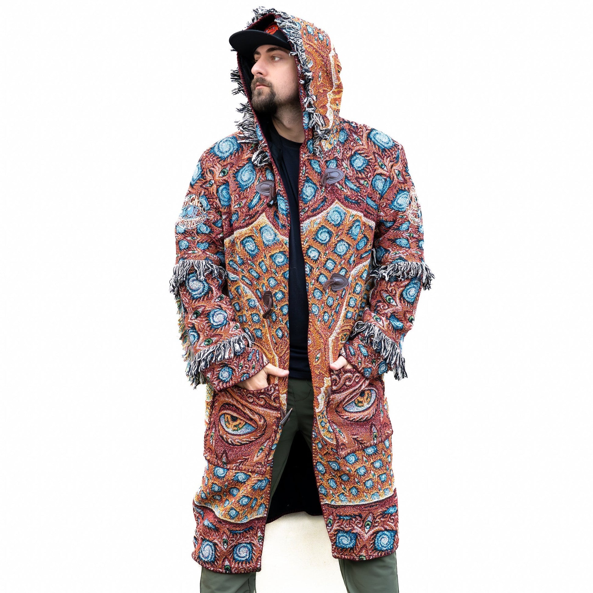 CoSM Shop unisex one-size woven cotton coat with a psychedelic eye pattern in red, blue, and gold. Features fringe details and toggle closures.
